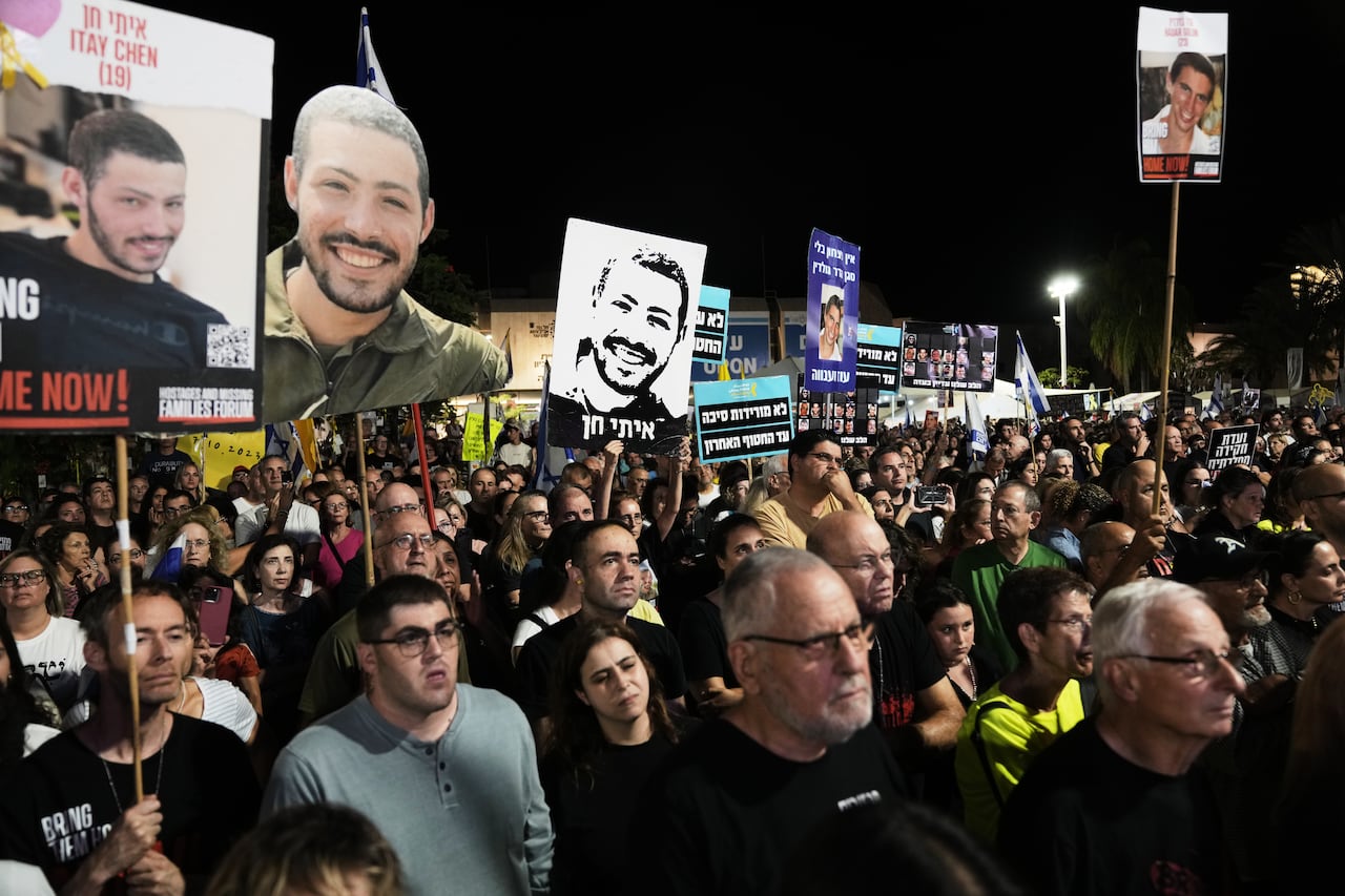 Crowds of people hold signs and pictures of their loved ones on them