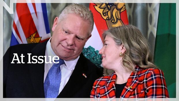Susan Holt, Premier of New Brunswick, whispers to Ontario Premier Doug Ford, chair of the Council of the Federation, during a press conference with the premiers of Canada in Washington, D.C., U.S., February 12, 2025. A man in a suit leans towards a woman in a red plaid jacket.
