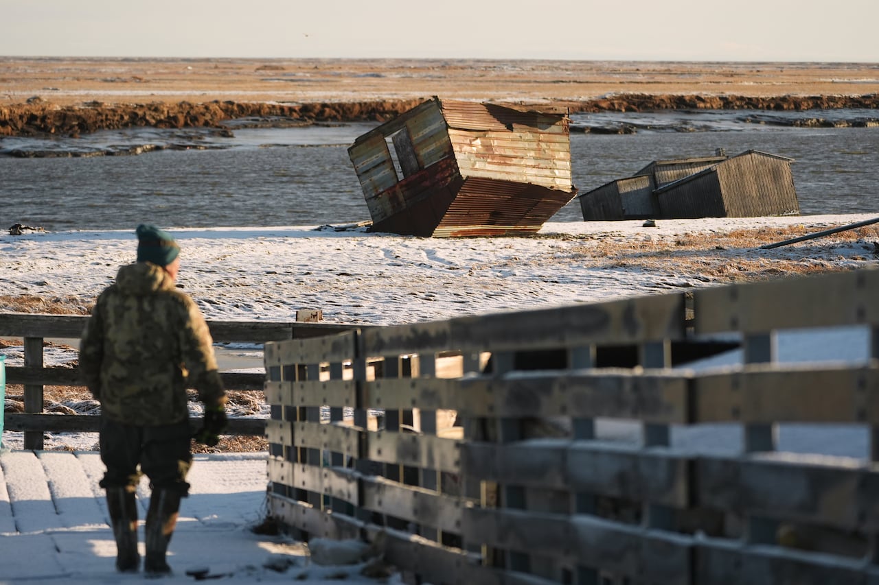 A antheral walking a snowy boardwalk adjacent immoderate overturned buildings.