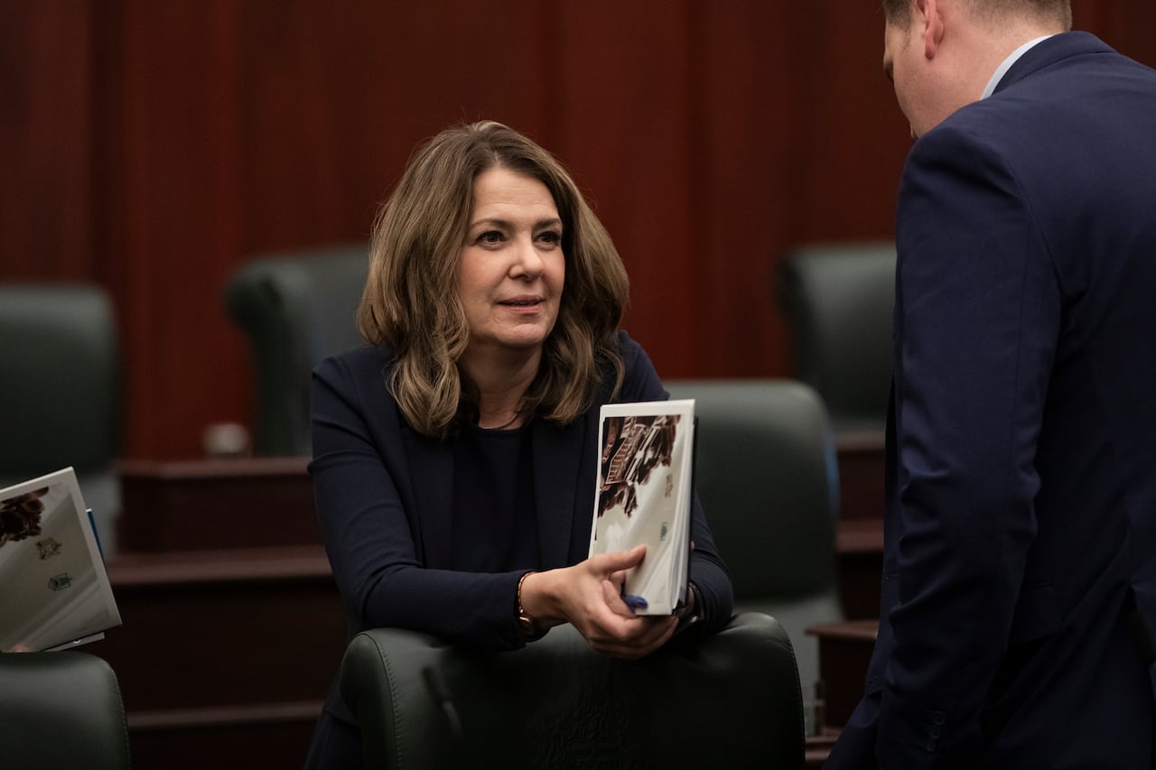 A woman in blue holds a document in her hand.