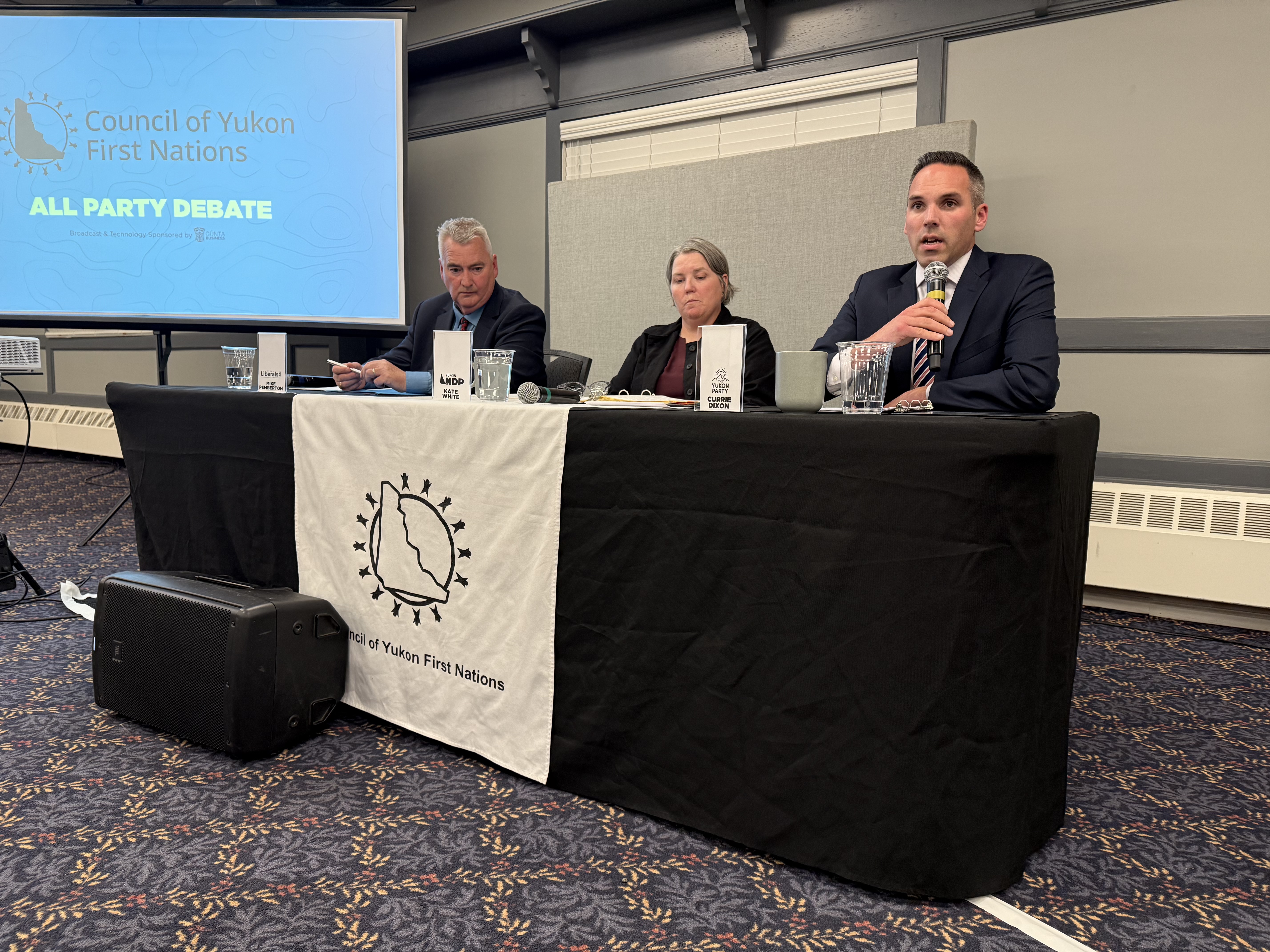 Liberal Leader Mike Pemberton, left, NDP Leader Kate White, middle, and Yukon Party Leader Currie Dixon. All took part in a debate organized by the Council of Yukon First Nations in Whitehorse on Oct. 8. The three leaders sit a table with CYFN flag hanging down from it in a downtown Whitehorse banquet hall.
