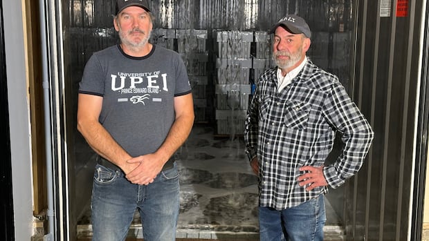 Wally MacPhee (left) and Mark Prevost (right) at Bait Masters in Nine Mile Creek, P.E.I. Two men stand in front of a tank with overhead sprinklers