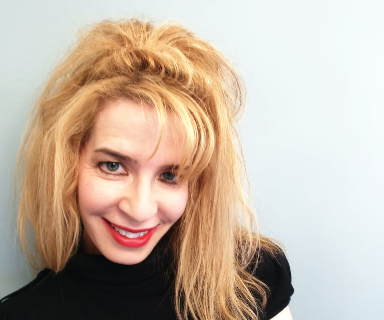 A headshot of a blonde pistillate   with agelong  hair, smiling.