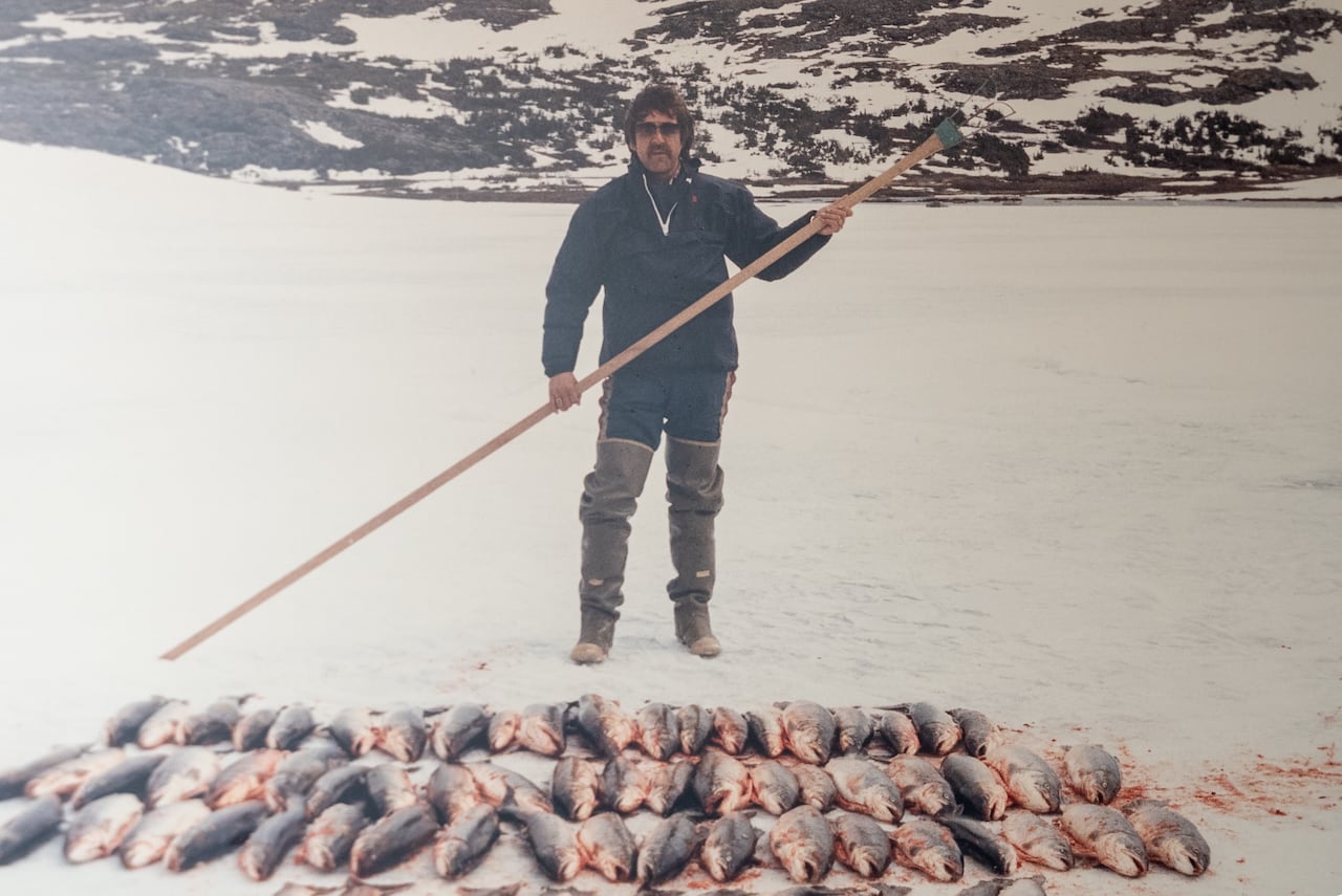 man with harpoon stands in front of dozens of dead fish