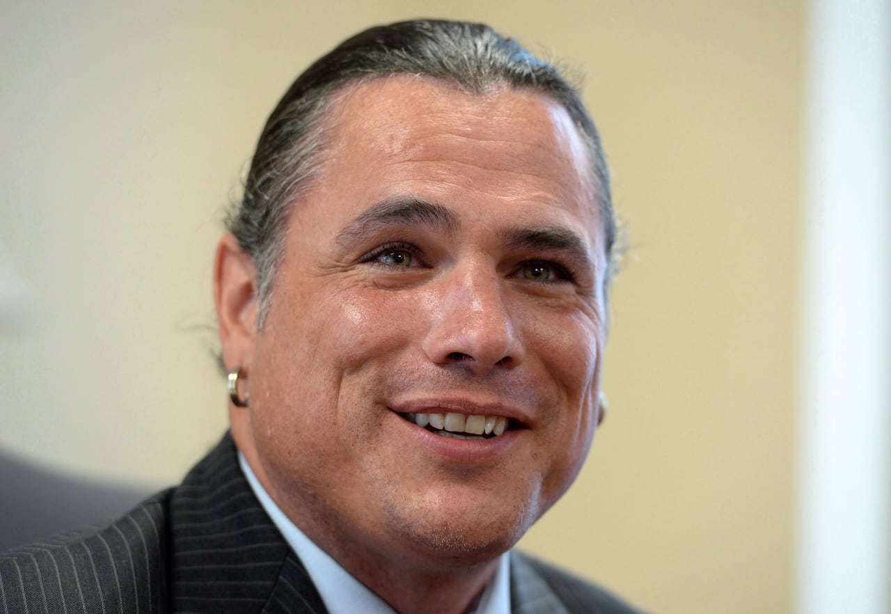 Una persona con aretes mira a la cámara con una sonrisa.