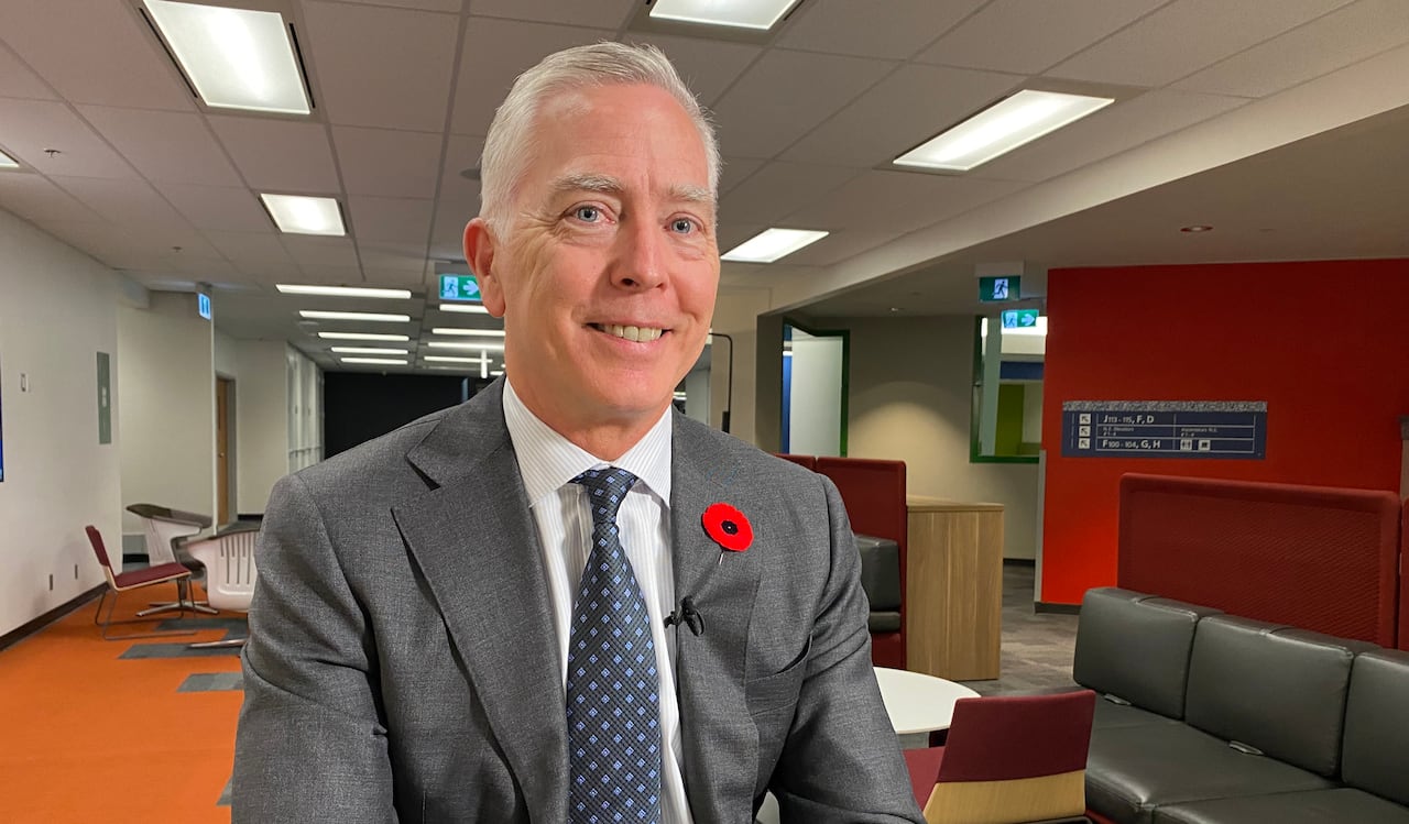 A man sits at a table wearing a suit and tie. 