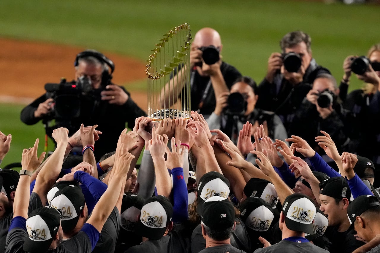 a group of baseball players lifting a trophy into the air