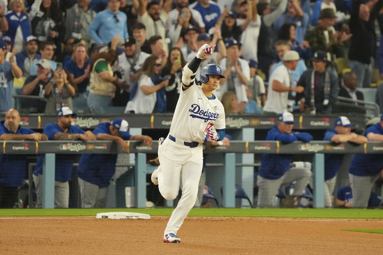 a man in a white baseball uniform runs between two plates with his arm raised