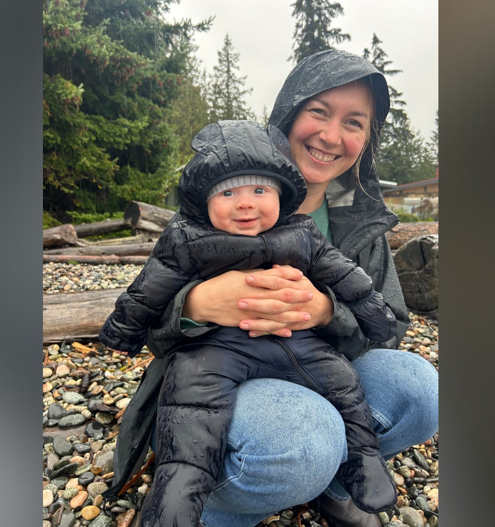 A woman in a rain jacket holds a baby