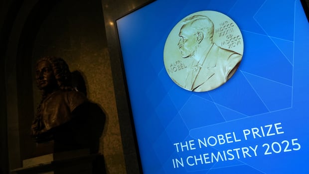 A large replica of a coin with a man's portrait is shown on a wall. The writing underneath says 'The Nobel Prize in Chemistry 2025.'