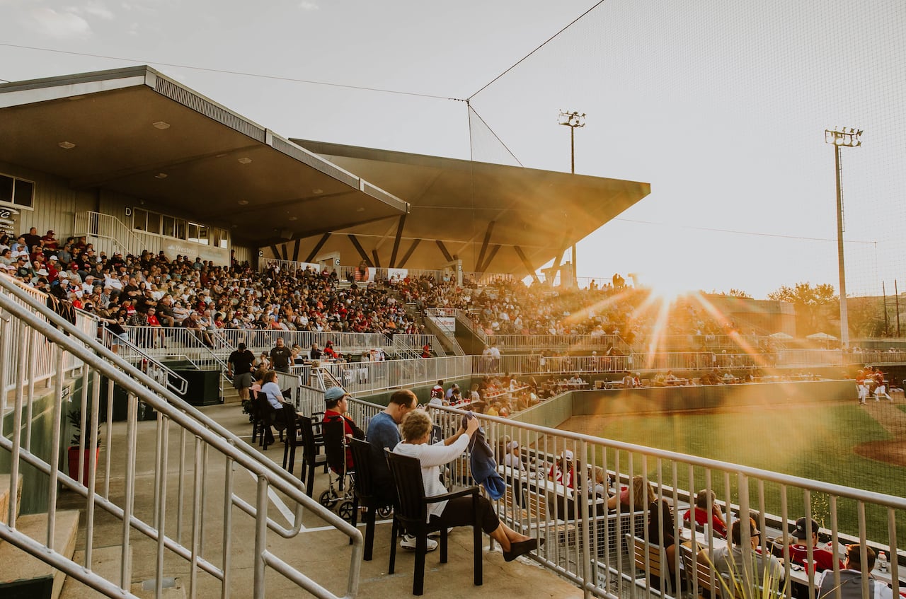 The sun shines brightly on a stadium full of fans watching baseball
