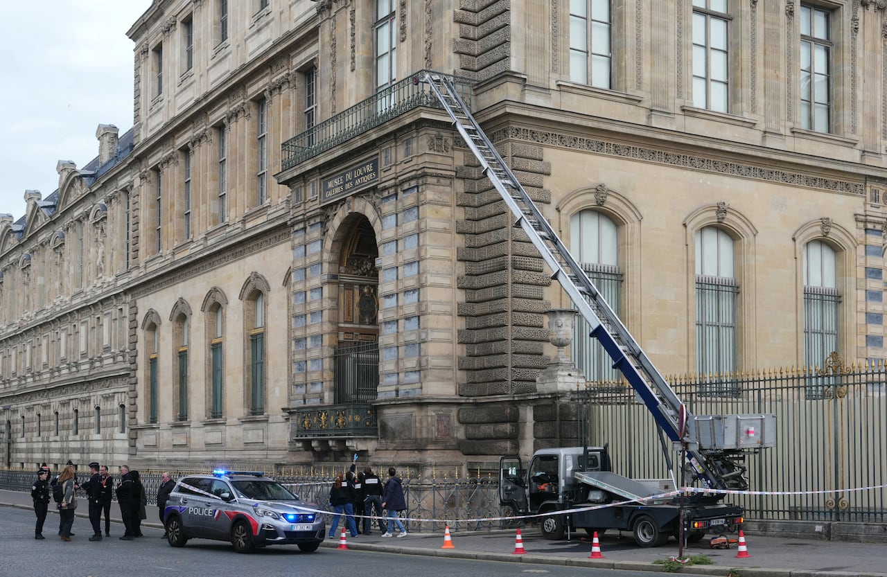 Police gather around a service crane near a building.