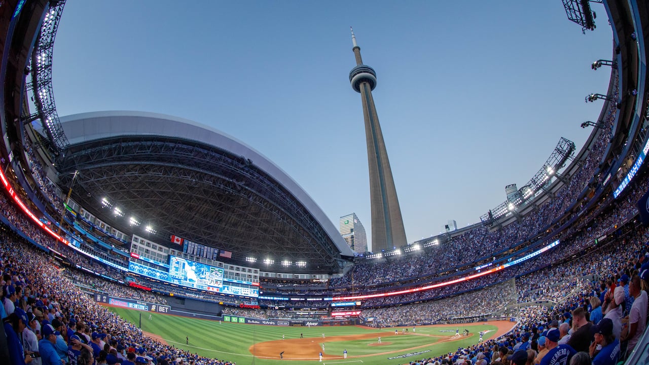 A fishbowl view of the Rogers Centre at dusk in October with a full crowd, baseball field, and CN Tower in view