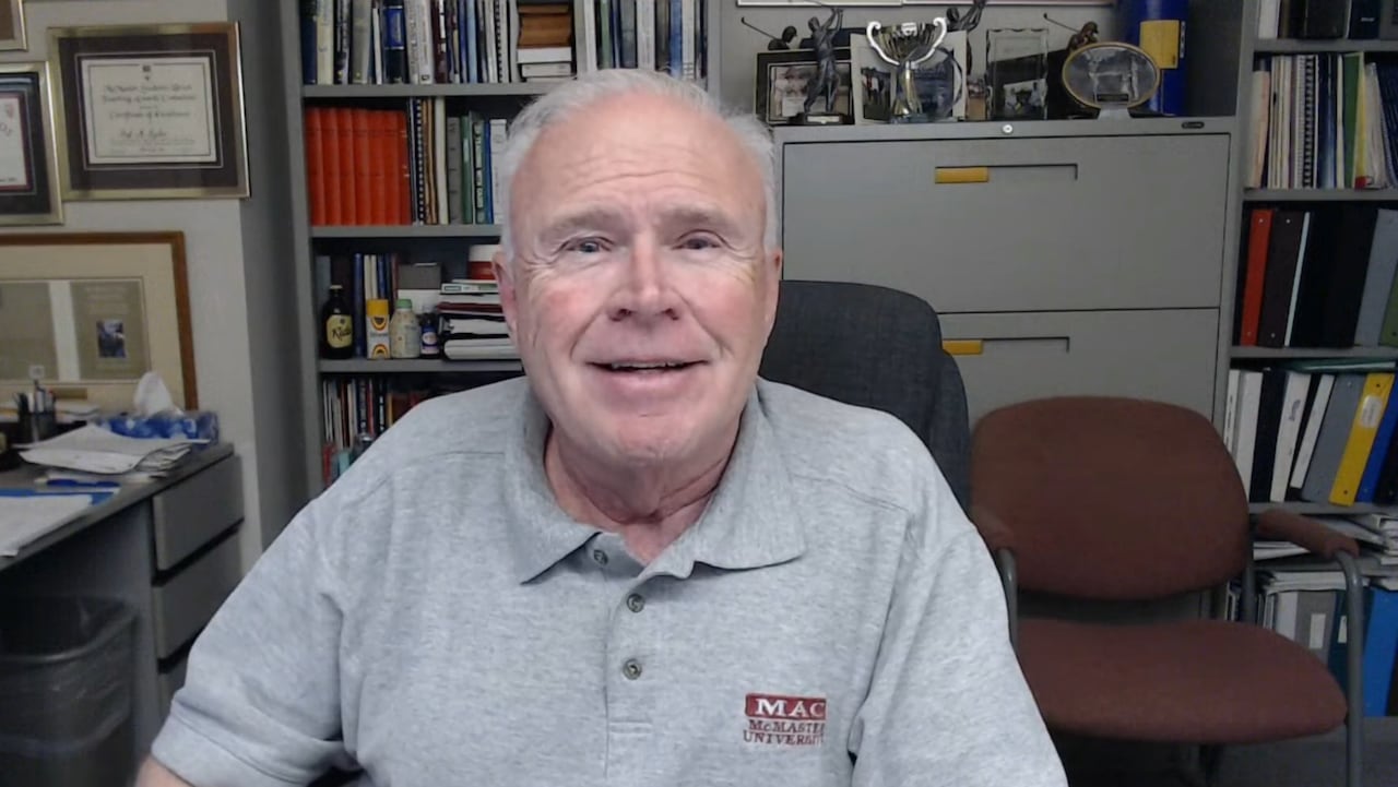 A man in a grey shirt smiles into the camera.