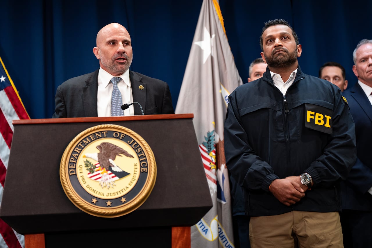 A man in a suit speaks from a podium called the Department of Justice.