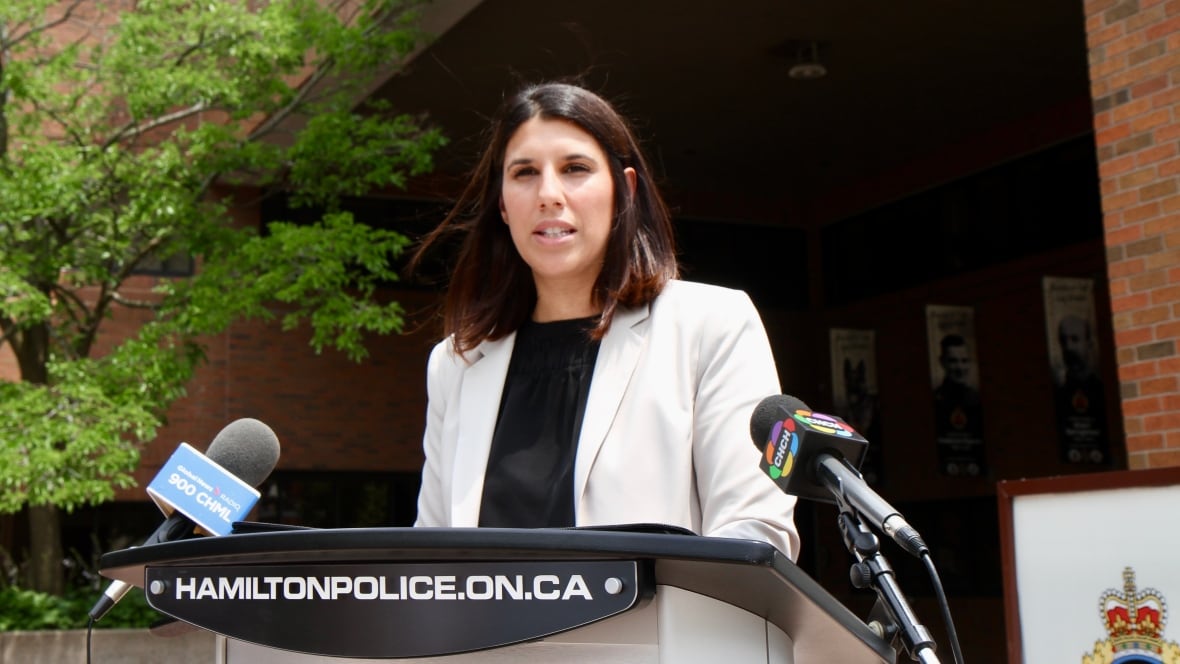 Woman dressed in white jacket speaks at the podium.
