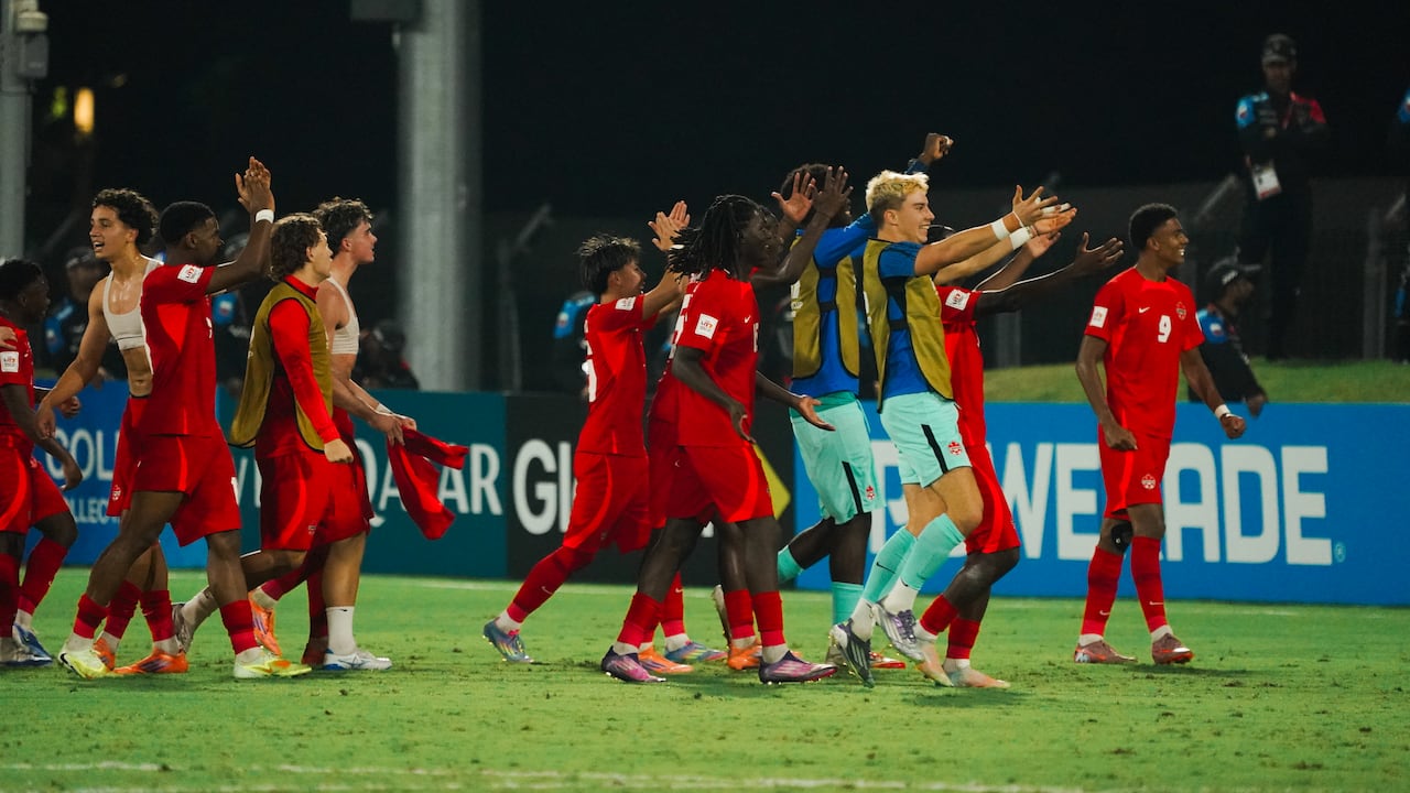 Male soccer players representing Canada celebrate on the field.