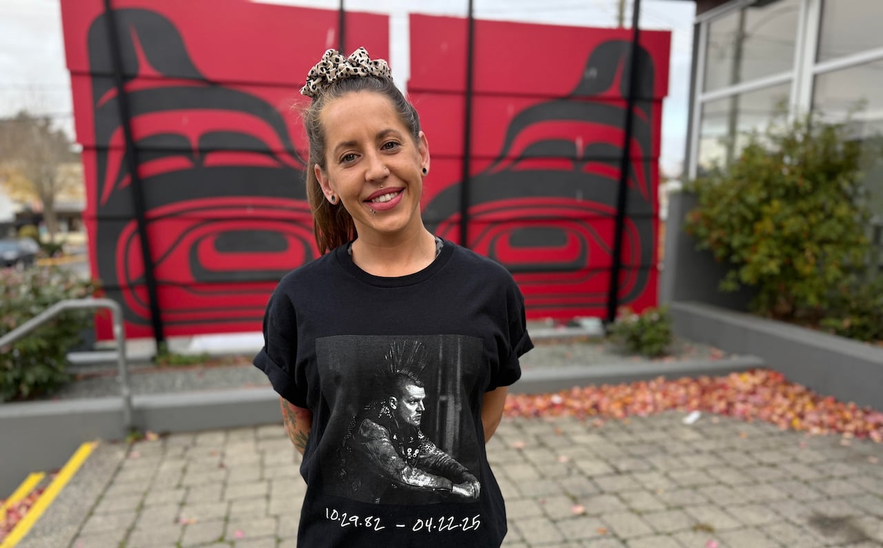 A woman with a black t-shirt stands smiling.
