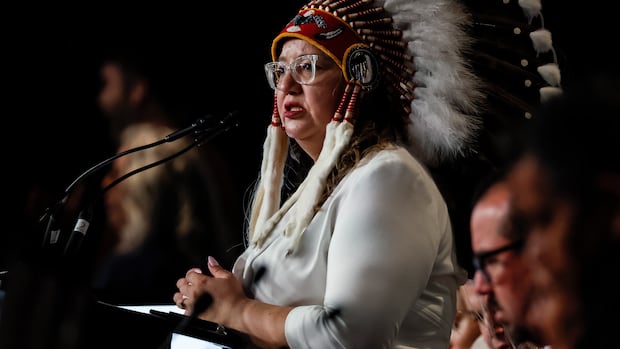A woman in a headdress speaks into a microphone.