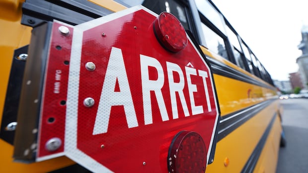 The side of a school bus with focus on the stop sign on the side