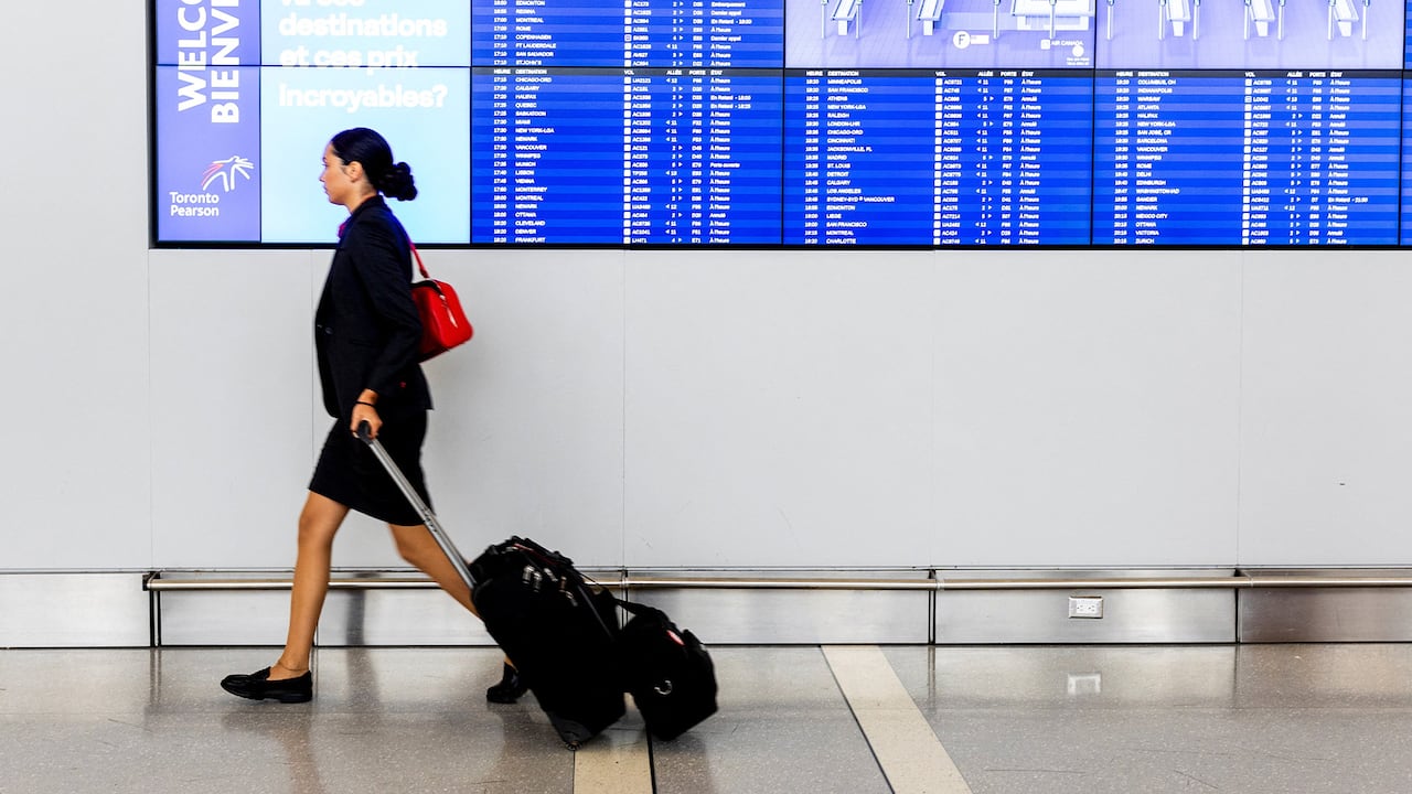 A woman walks and pulls luggage. 