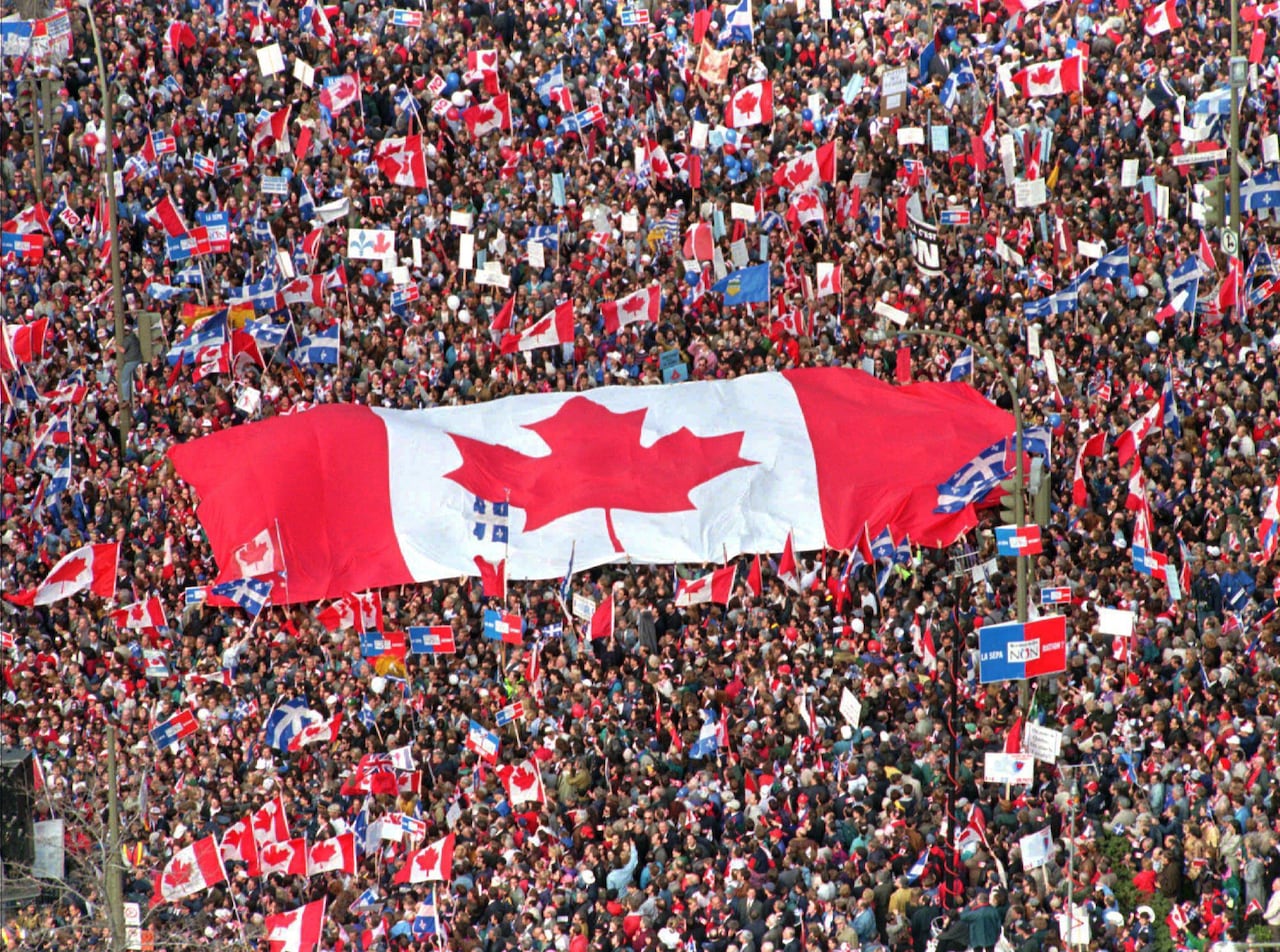 Una enorme bandera canadiense y una gran multitud.