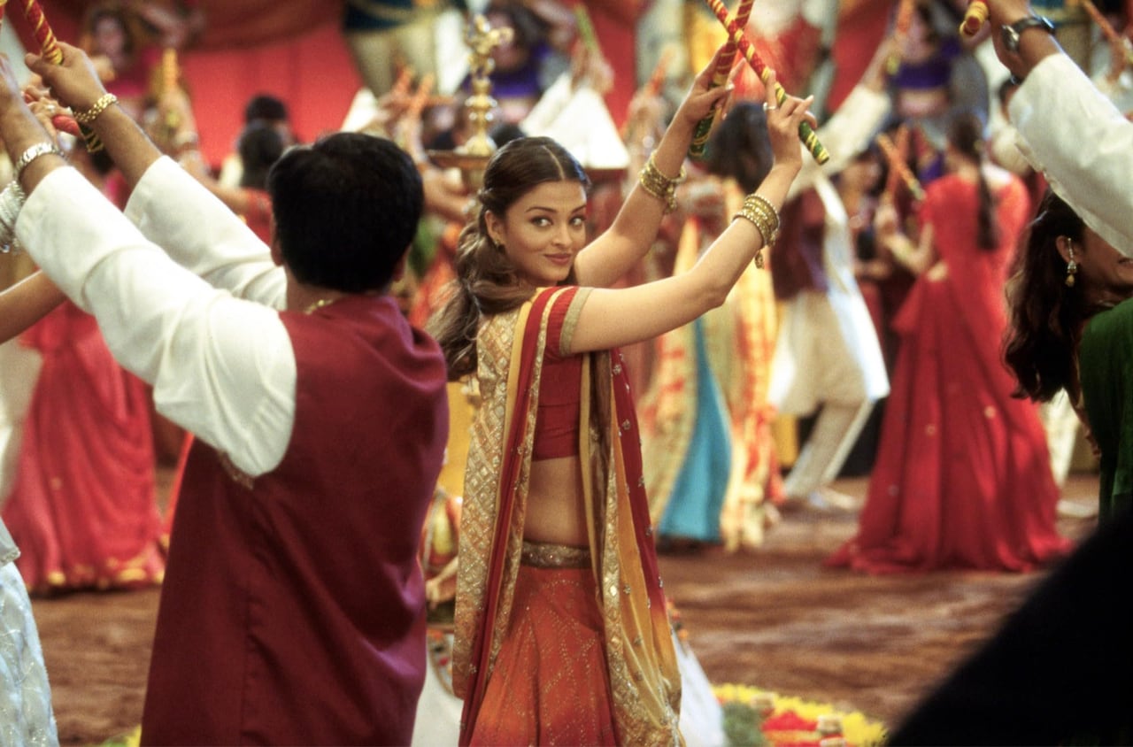A woman dances, looking over her shoulders at a man. 