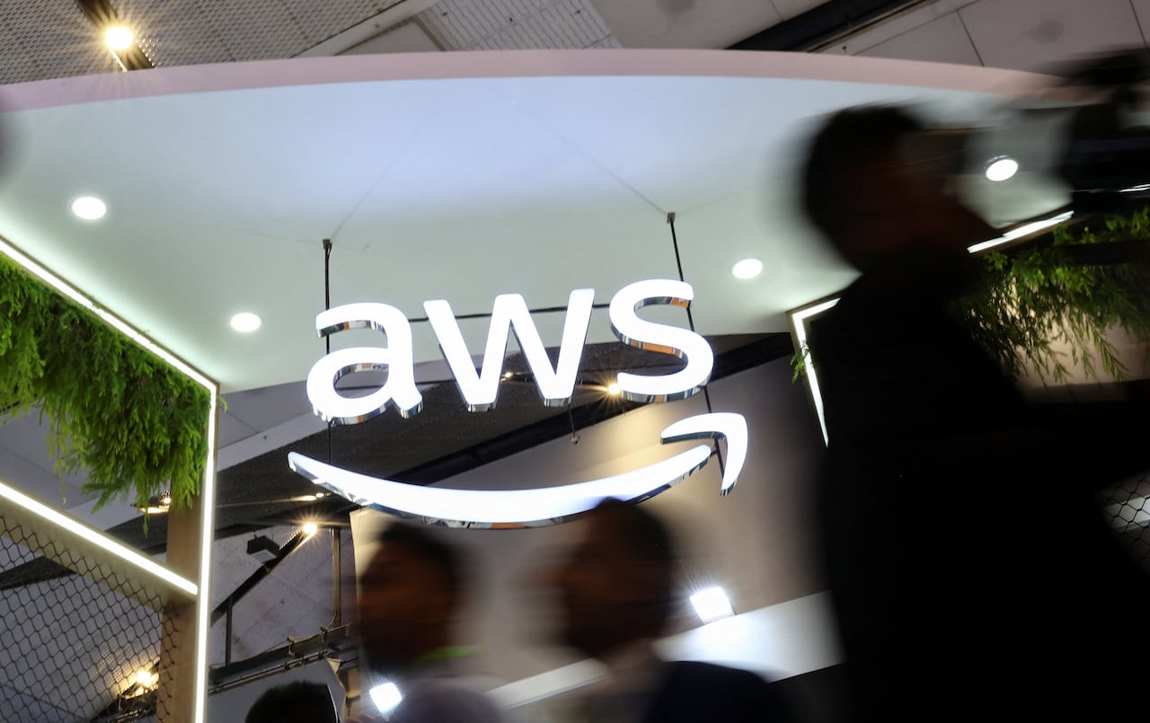 A large logo reading AWS is suspended from a convention centre ceiling.