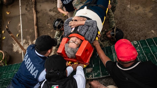 A woman on a stretcher with her neck in a brace, as rescue workers move her in the aftermath of heavy rains that caused flooding.