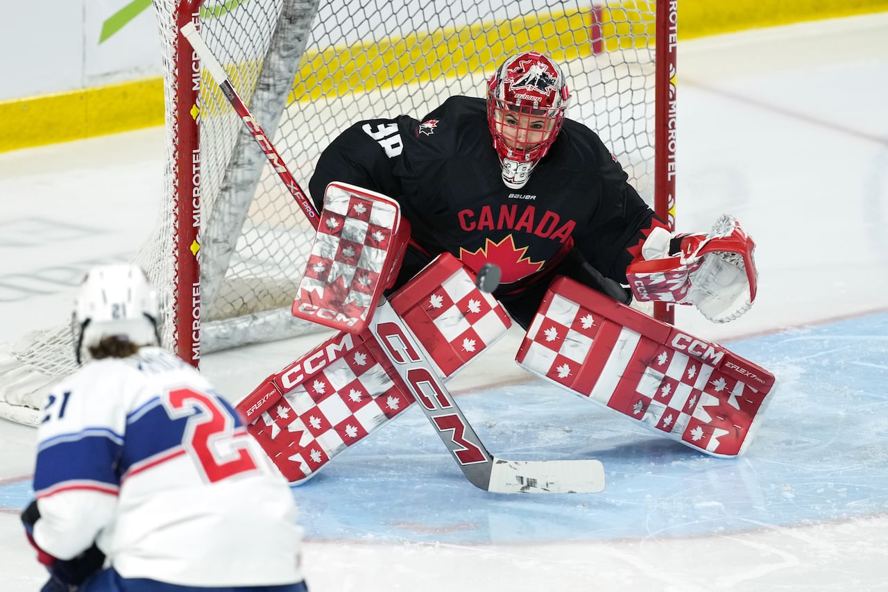 Team Canada's goalie makes a save during a hockey match.