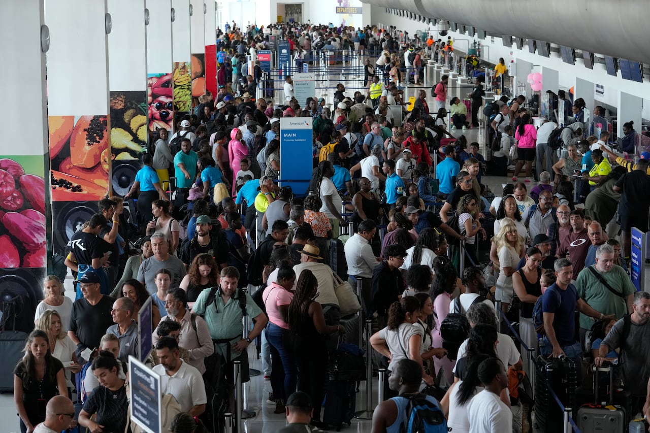 wide shot of an airport, crowded with passengers waiting to check in 