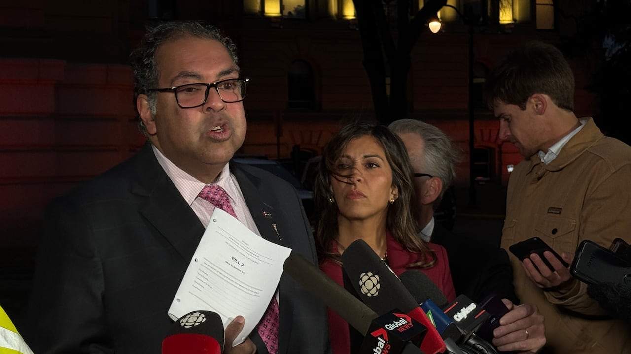 Alberta NDP leader Naheed Nenshi holds a copy of Bill 2 while speaking to reporters outside the Alberta legislature Monday evening.