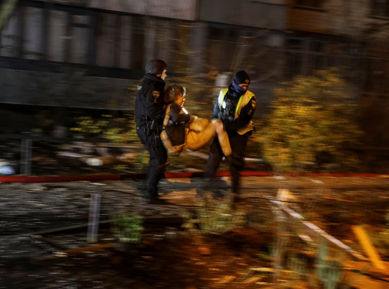Two rescue workers carry a person out of a building.